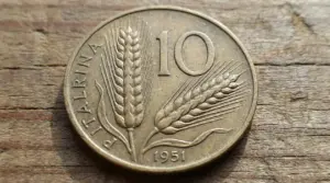 Moneta da 10 lire del 1951 con spighe di grano su sfondo in legno