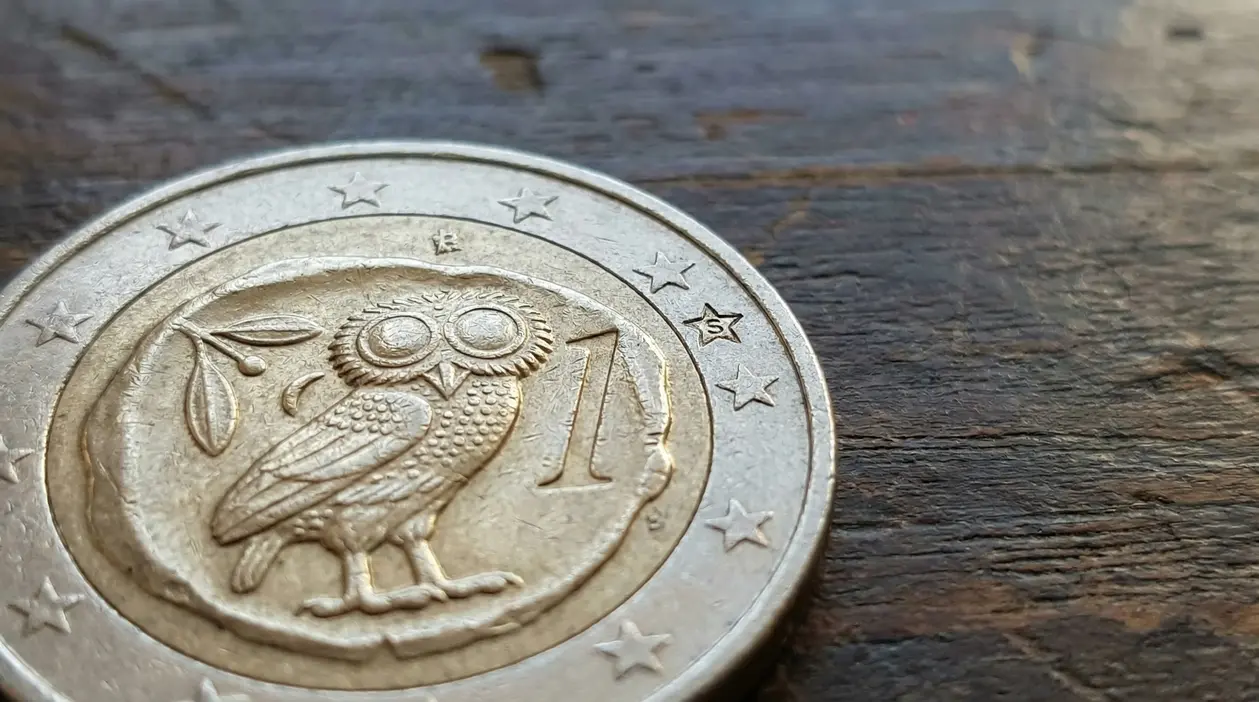 Moneta da 1 euro greca con simbolo del gufo su sfondo in legno