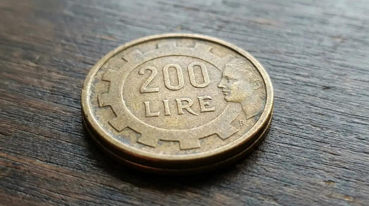 Moneta da 200 lire italiana appoggiata su una superficie in legno