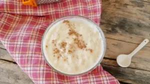 Ciotola di besciamella leggera con spolverata di noce moscata su tovagliolo a quadretti