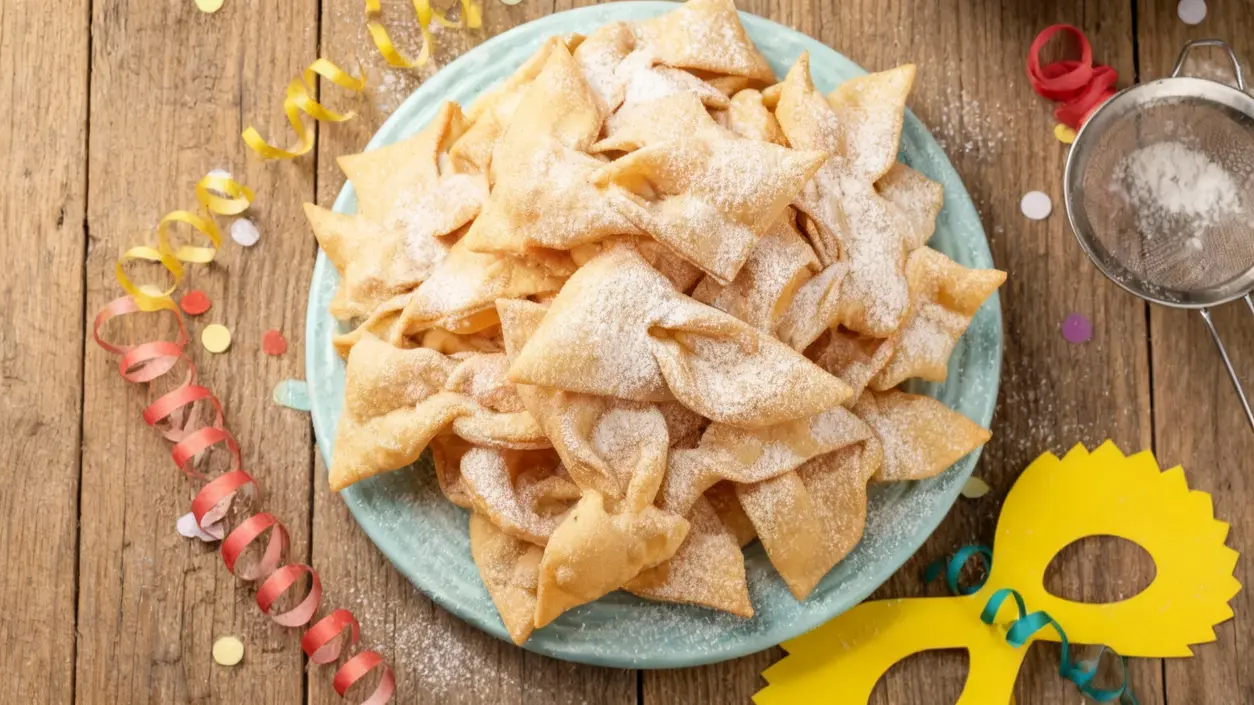 Vassoio di chiacchiere croccanti spolverate di zucchero a velo su tavolo in legno