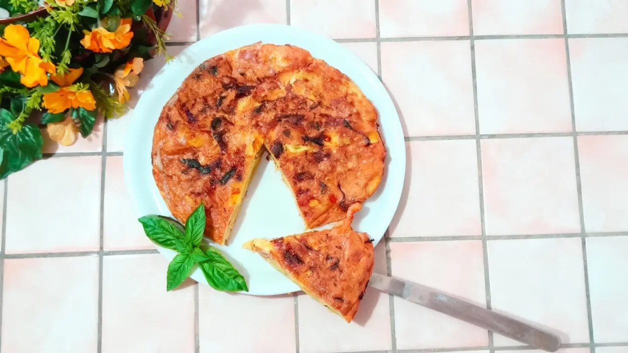 Frittata alta e soffice su un piatto bianco con una fetta tagliata e decorazione di basilico