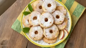 Frittelle di mele al forno disposte su un piatto decorato, spolverate con zucchero a velo