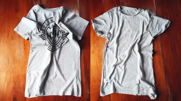 Due magliette grigie stropicciate appoggiate su un pavimento in legno