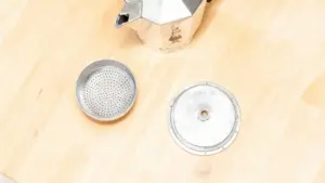 Componenti smontati di una moka su un piano in legno chiaro
