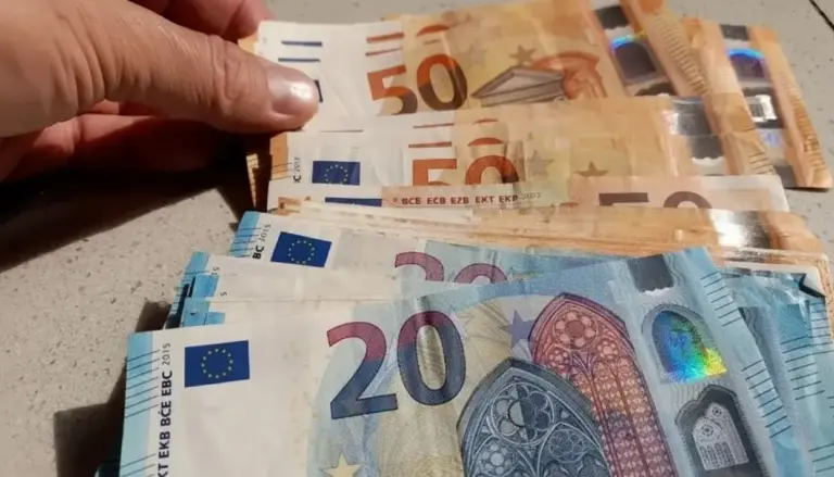 Banconote da 20 e 50 euro disposte su un tavolo con una mano che le tiene