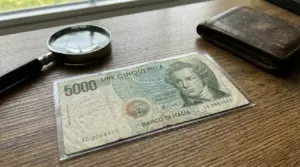 Vecchia banconota da 5.000 lire italiana protetta in una custodia su un tavolo in legno