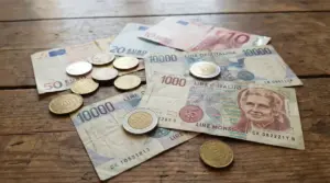 Monete e banconote in lire italiane ed euro su un tavolo di legno