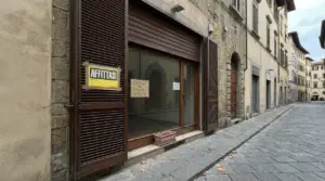 Negozio chiuso con cartello 'affittasi' in una strada deserta
