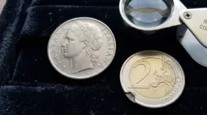 Due monete su sfondo nero, una coniata italiana e una da 2 euro con danno visibile