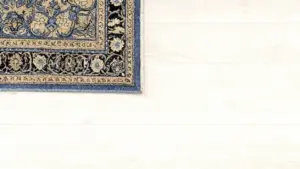 Dettaglio del bordo di un tappeto orientale con motivi floreali su pavimento chiaro
