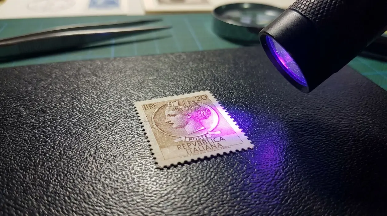 Francobollo da 20 lire Siracusana illuminato da luce UV su sfondo scuro