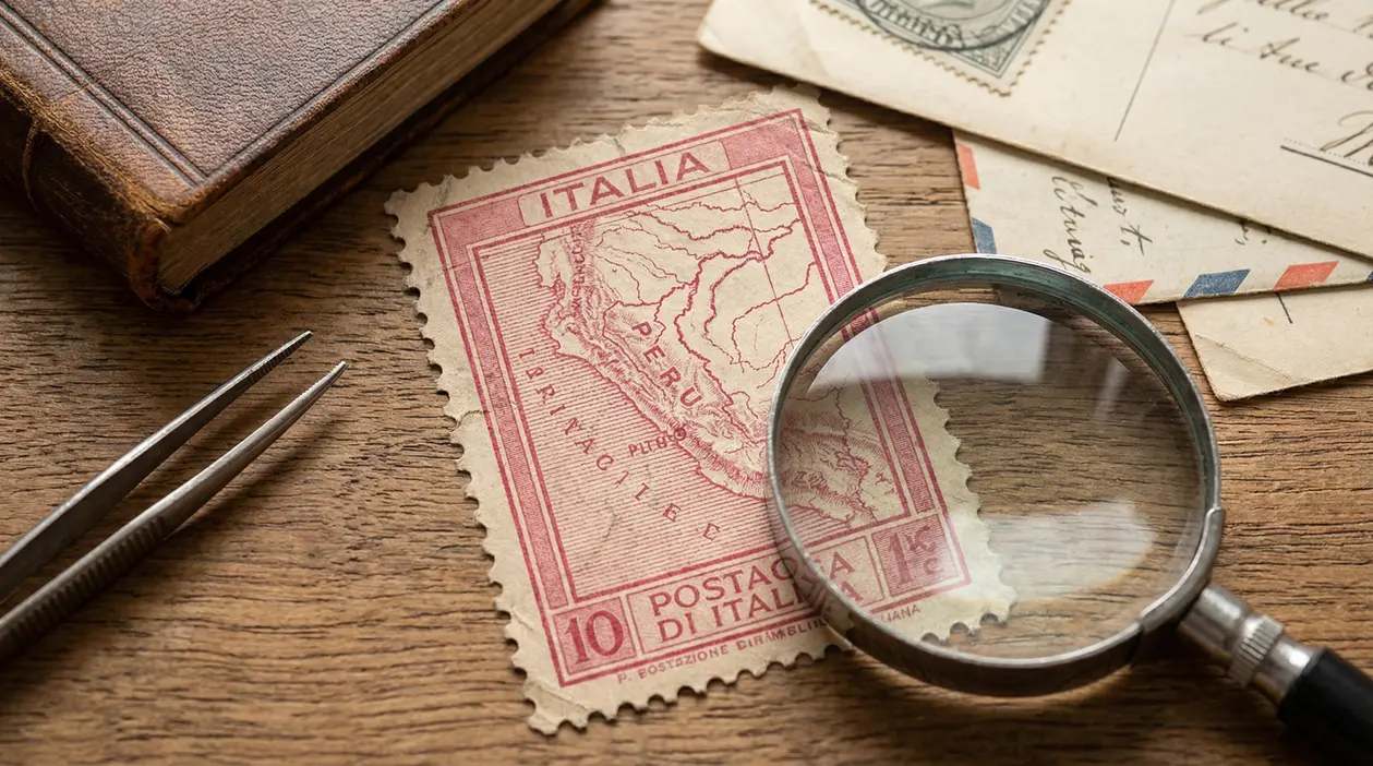 Francobollo italiano Gronchi Rosa osservato con lente d'ingrandimento su tavolo di legno