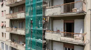 Operai su impalcature eseguono lavori urgenti su balconi danneggiati di un edificio residenziale