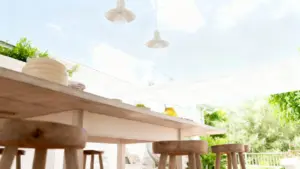 Tavolo in legno sotto una veranda luminosa con sedie e stoviglie