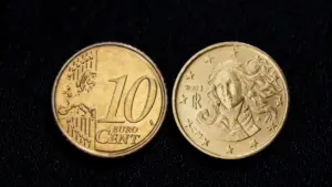 Due monete da 10 centesimi di euro su sfondo nero, una con volto artistico.