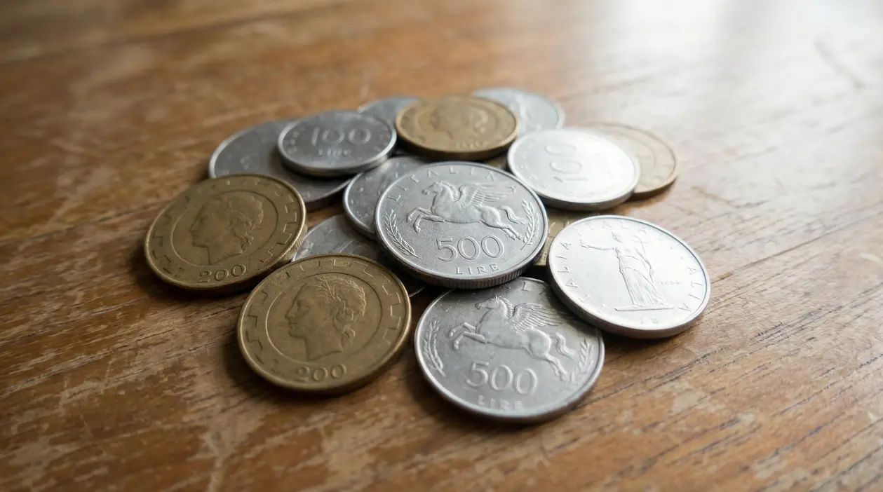 Vecchie monete italiane in lire sparse su un tavolo in legno
