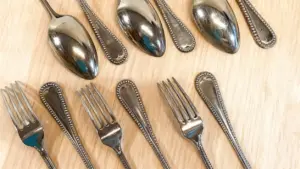 Vecchie posate in alpacca disposte su un tavolo di legno chiaro