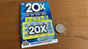 Biglietto gratta e vinci 20X con una moneta da un euro su tavolo in legno