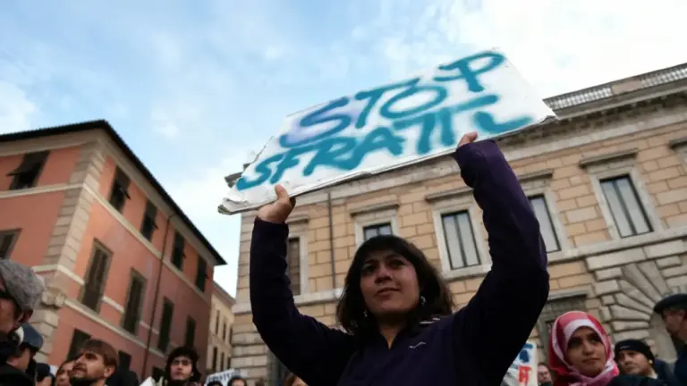 Donna solleva un cartello durante una manifestazione contro gli sfratti in una città italiana