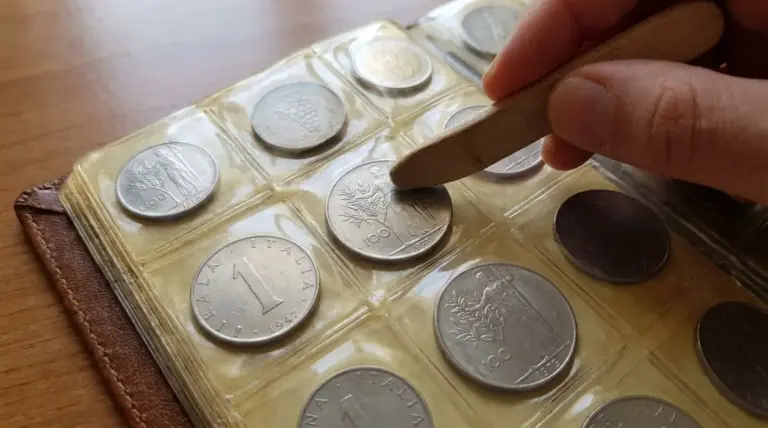 Mano che utilizza uno strumento di legno per rimuovere una moneta da un album da collezione