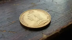 Vecchia moneta d’oro britannica con profilo di regina su superficie in legno