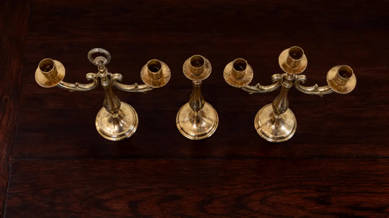 Tre vecchi candelabri in ottone su tavolo in legno scuro