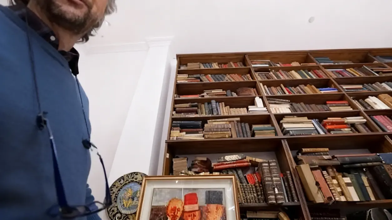 Dipinto incorniciato davanti a una libreria piena di libri antichi in una casa