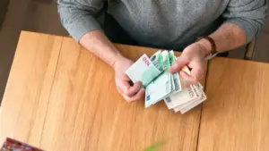 Persona conta banconote da cinquanta e cento euro su un tavolo di legno