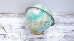 Vecchio mappamondo scolastico su base metallica dorata poggiato su tavolo di legno chiaro