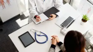 Medico durante una visita con una persona seduta al tavolo per un controllo sanitario